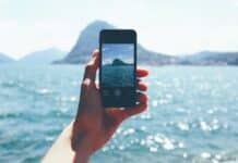 Как да предпазим телефона на плажа? hand holding cellphone taking photo of ocean